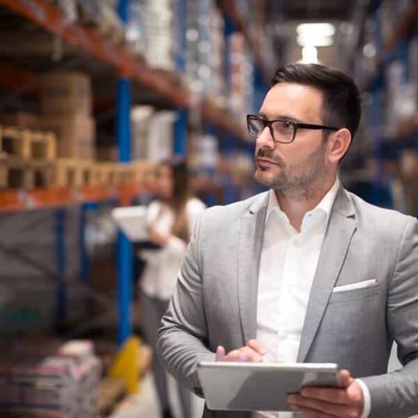 Manager reviewing inventory on a tablet in a warehouse